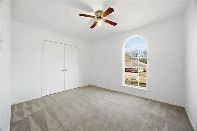 an empty room with windows and ceiling fan