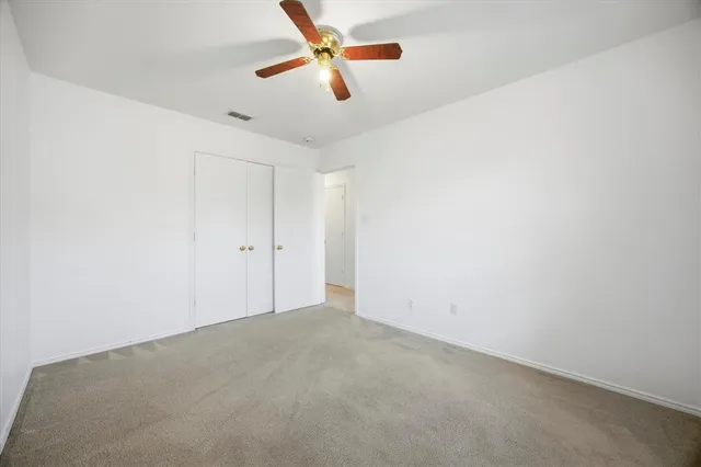 an empty room with a ceiling fan and window