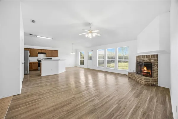 a view of a livingroom with a fireplace a ceiling fan and wooden floor