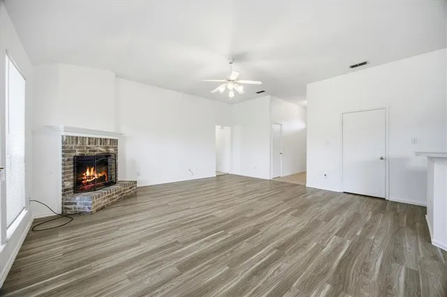 an empty room with wooden floor fireplace and windows