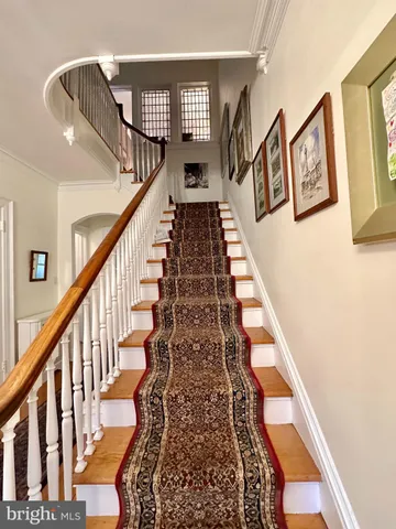 a view of staircase with lots of frames on wall and a large window