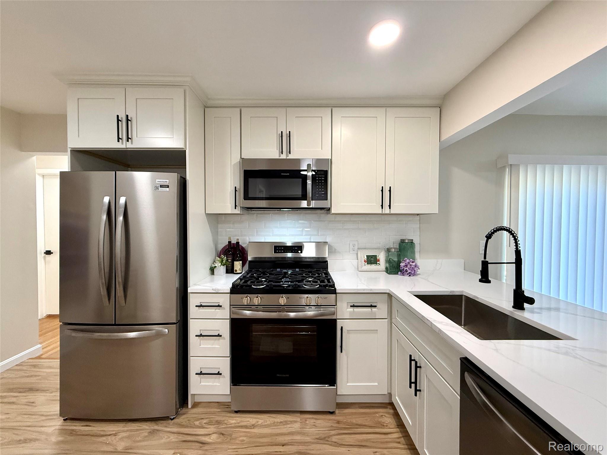 39909 Lynn Street Canton, MI 48187 - Photo 7 of 45 Kitchen featuring white shaker-style cabinetry, stainless steel appliances, a white subway tile backsplash, and light-toned countertops