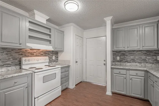 a kitchen with granite countertop a stove a sink and a refrigerator