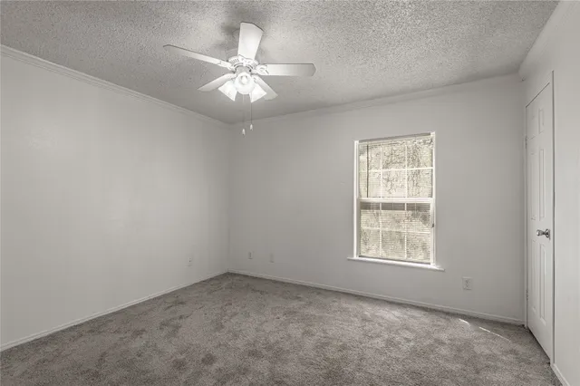 an empty room with a chandelier fan and windows