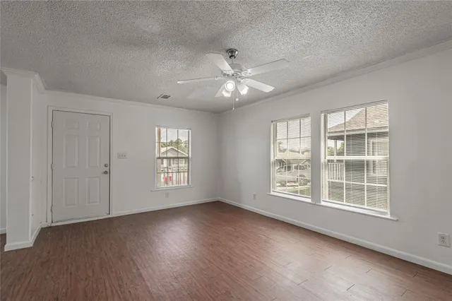 a view of an empty room with a window and wooden floor