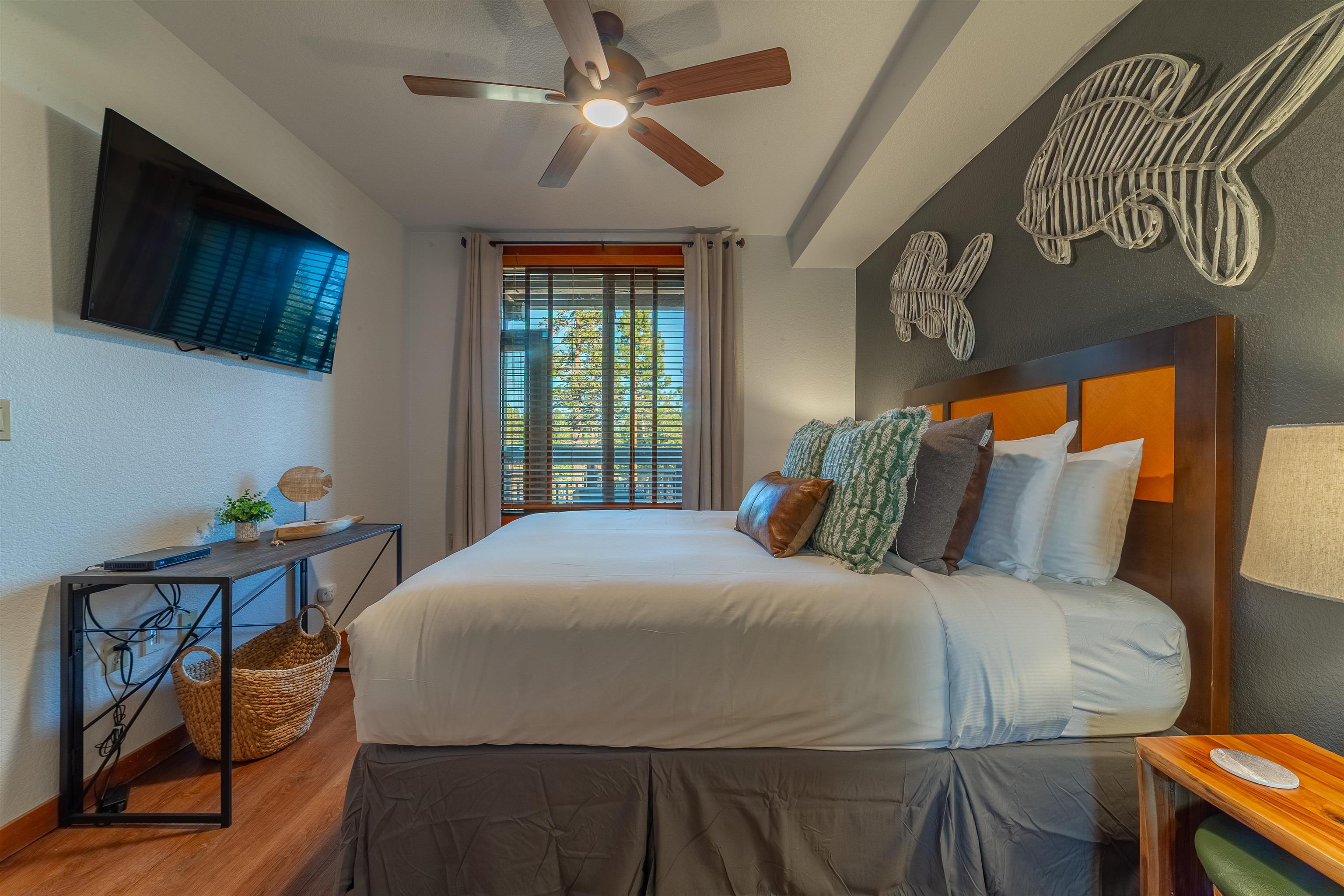 6201 Minaret Road, Unit 2221 Mammoth Lakes, CA 93546 - Photo 25 of 44 Bedroom featuring wood-finish flooring, a ceiling fan, a window with horizontal blinds, a wall-mounted flat-screen television, and an accent wall