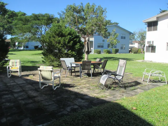 a view of a patio with table and chairs near a garden