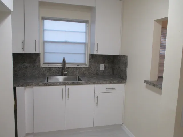 a kitchen with granite countertop white cabinets and sink