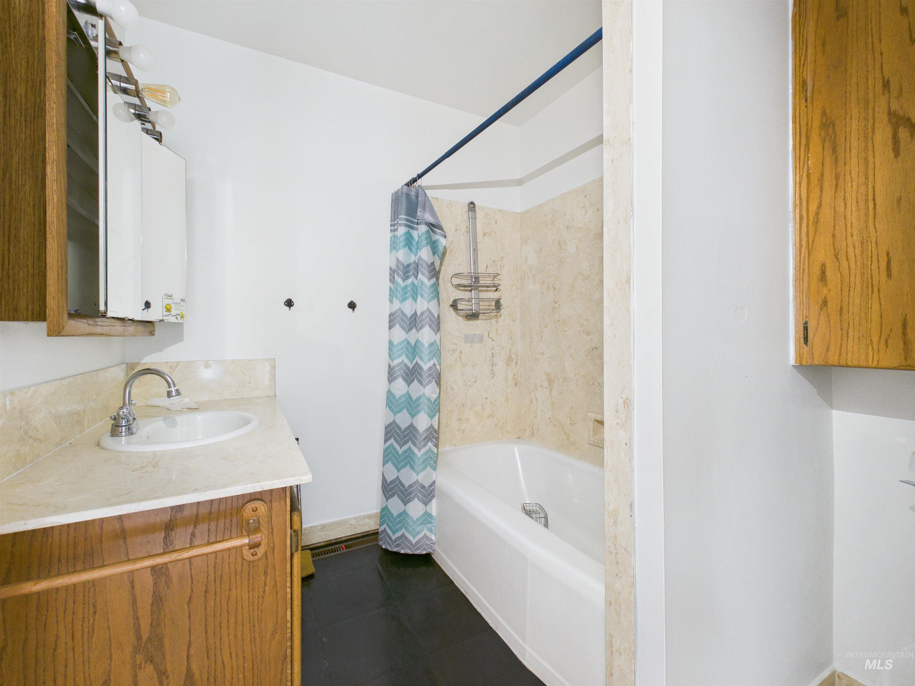 810 South D Street Rupert, ID 83350 - Photo 14 of 23 Full bath with vanity, shower / bath combo with shower curtain, and dark tile patterned flooring