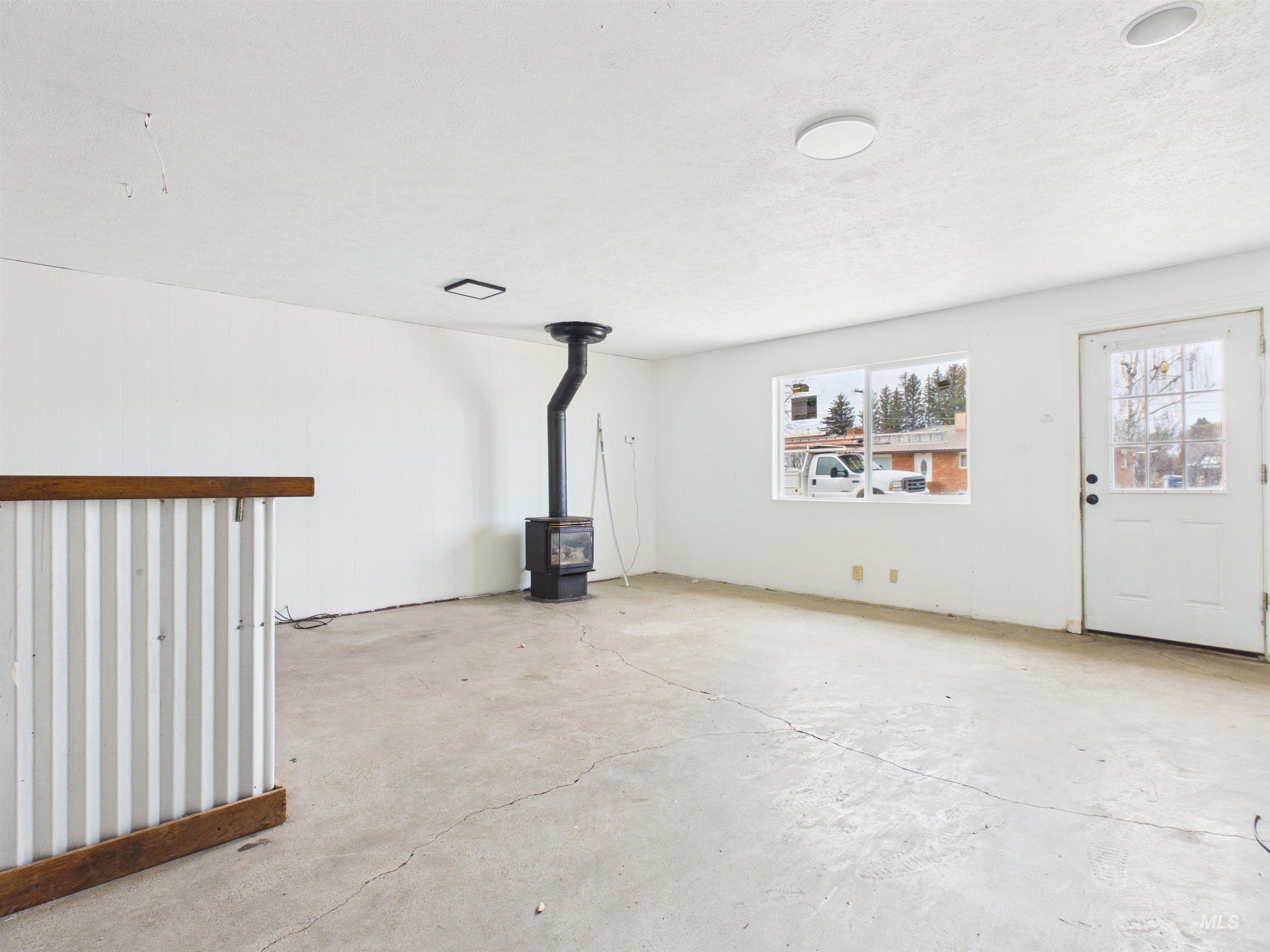 810 South D Street Rupert, ID 83350 - Photo 16 of 23 Unfurnished living room featuring a wood stove and unfinished concrete floors