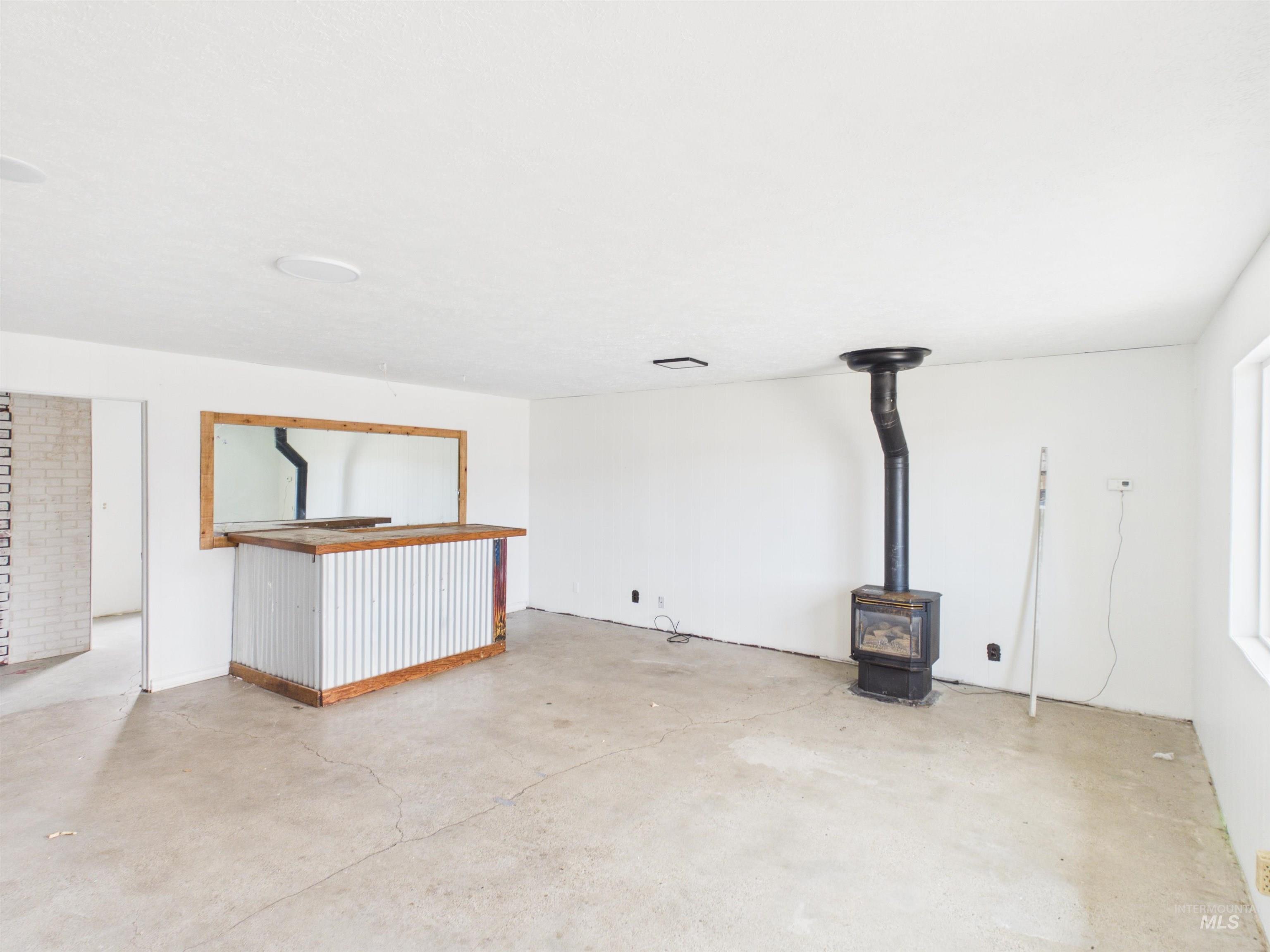 810 South D Street Rupert, ID 83350 - Photo 17 of 23 Unfurnished living room featuring a wood stove and concrete flooring