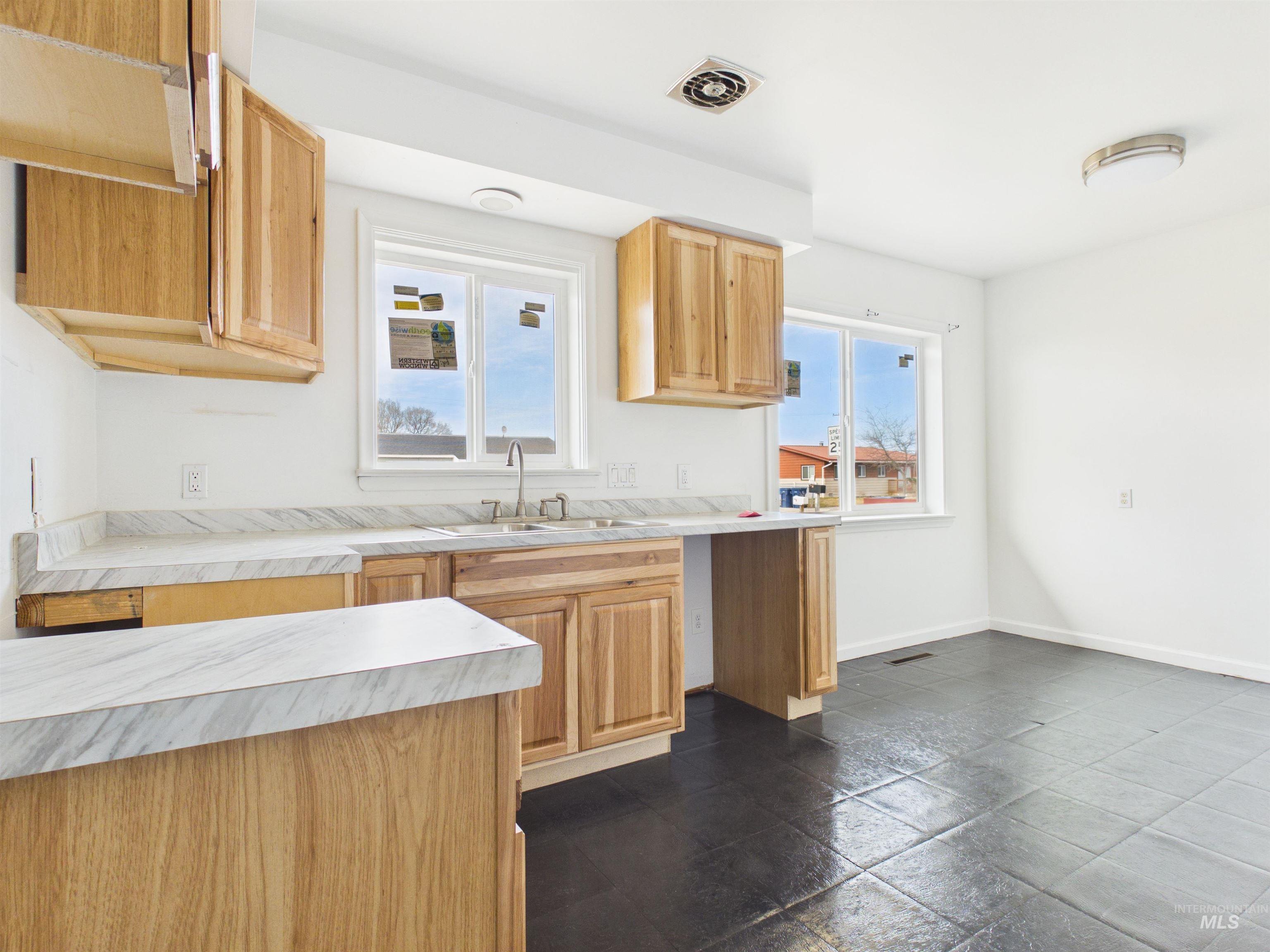 810 South D Street Rupert, ID 83350 - Photo 4 of 23 Kitchen with light countertops, light wood finish cabinets, plenty of natural light, and stone tile flooring