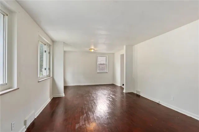 a view of an empty room with wooden floor and window