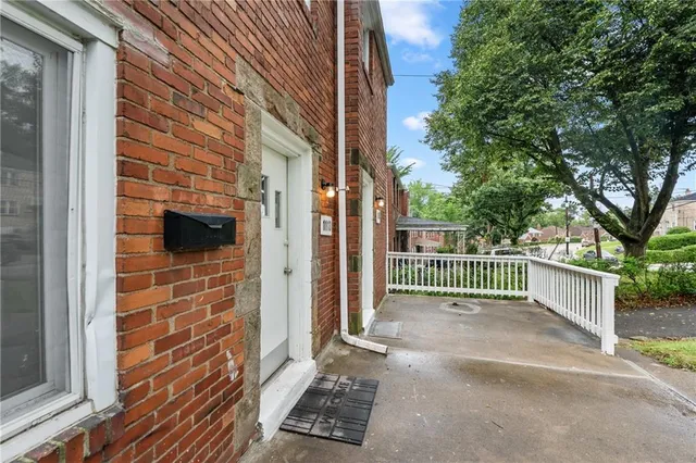 a view of a house with a small yard and large trees