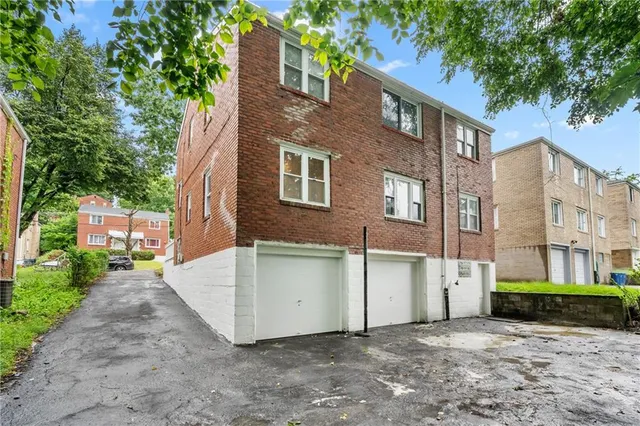 a view of a brick house with a yard and large tree