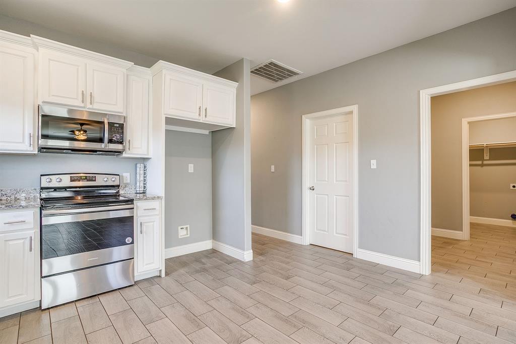 3901 Baylor Street Fort Worth, TX 76119 - Photo 17 of 40 a kitchen with granite countertop a stove and a refrigerator with white cabinets