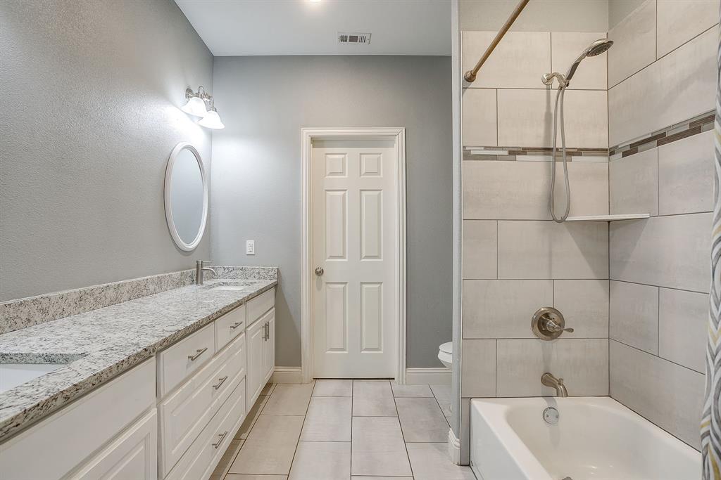 3901 Baylor Street Fort Worth, TX 76119 - Photo 29 of 40 a bathroom with a granite countertop sink a toilet and bathtub