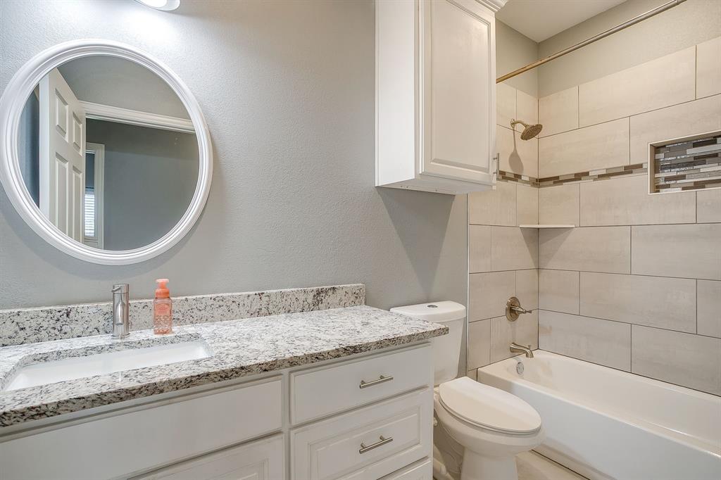 3901 Baylor Street Fort Worth, TX 76119 - Photo 33 of 40 a bathroom with a granite countertop toilet a sink and a mirror