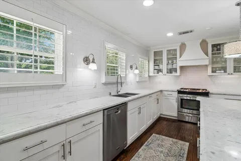 a kitchen with granite countertop stainless steel appliances a sink stove and cabinets