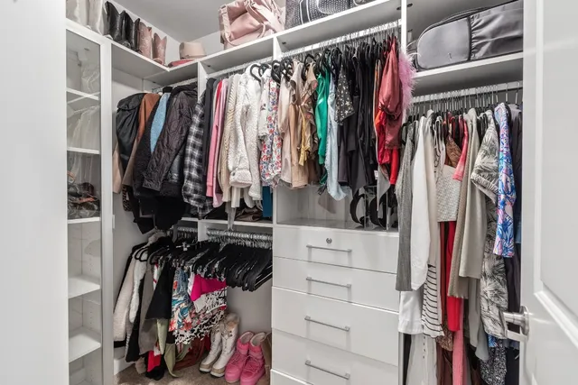 a view of walk in closet with clothes and shoes