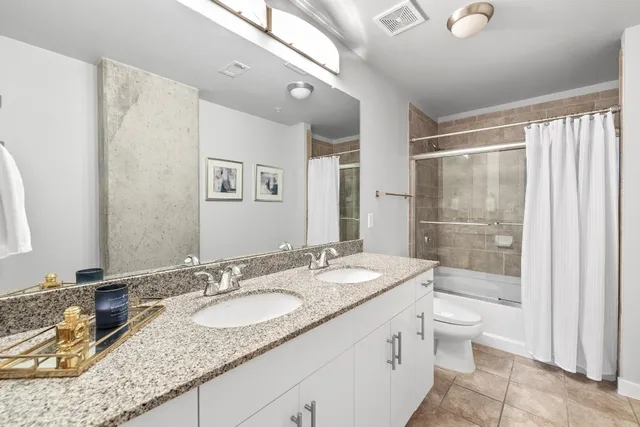 a bathroom with a granite countertop sink a toilet a mirror and shower