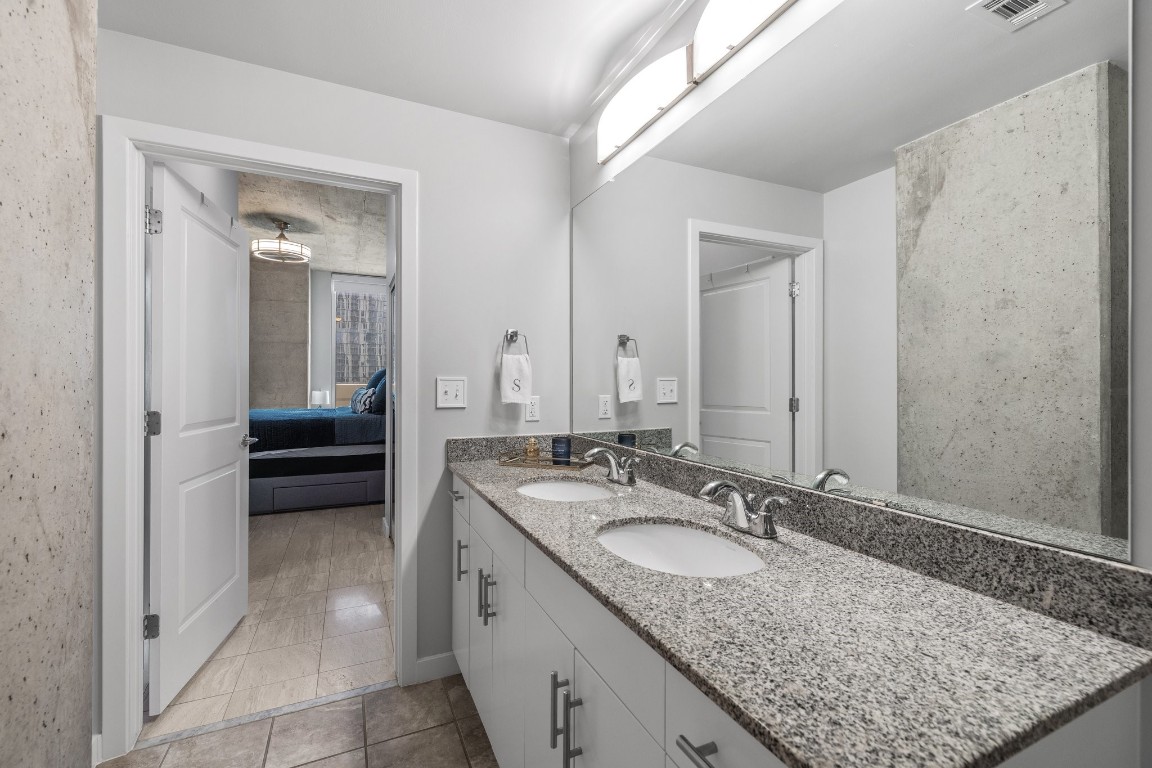 360 Nueces Street, Unit 911 Austin, TX 78701 - Photo 16 of 31 a en suite bathroom with a granite countertop sink and a mirror