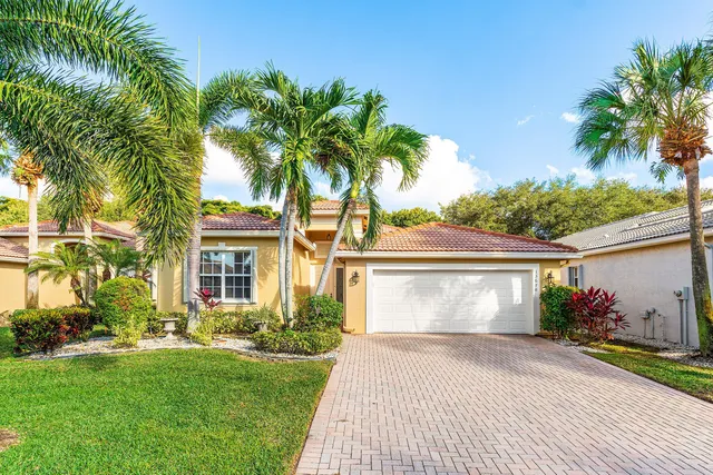 a front view of a house with a garden and palm trees