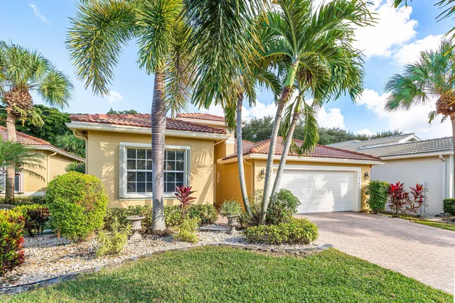 front view of a house with a yard and palm trees