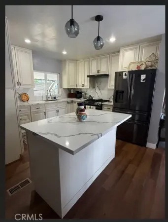 a kitchen with stainless steel appliances granite countertop a sink a stove a refrigerator and island