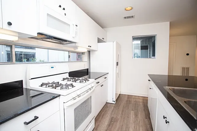 a kitchen with white cabinets and appliances