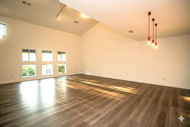 a view of empty room with wooden floor and fan