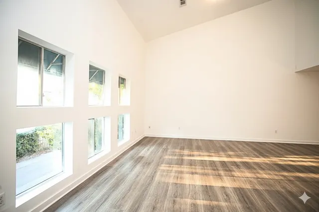 an empty room with wooden floor and windows