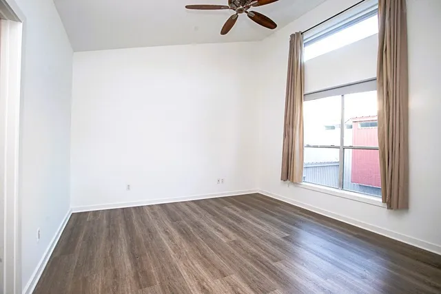 an empty room with wooden floor cabinet and windows