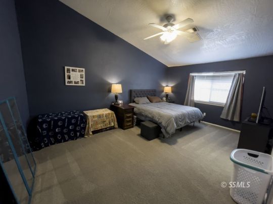 1411 Sims Street Ridgecrest, CA 93555 - Photo 22 of 35 a spacious bedroom with a bed and a chandelier
