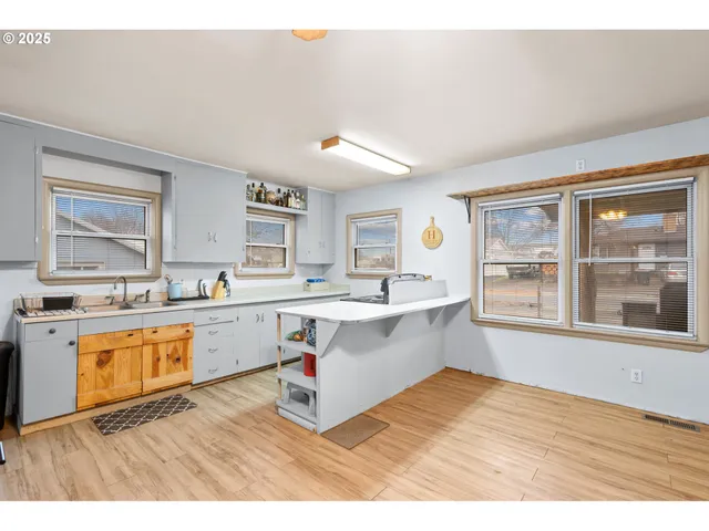 a kitchen with stainless steel appliances granite countertop a sink dishwasher and white cabinets with wooden floor