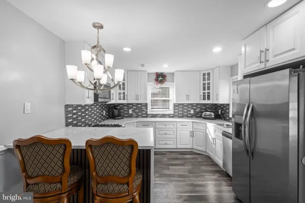 a kitchen with stainless steel appliances granite countertop a refrigerator a sink dishwasher a stove and a dining table with wooden floor