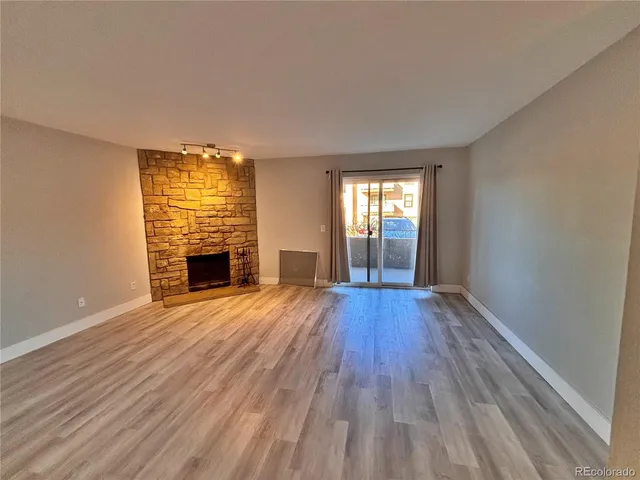 a view of empty room with wooden floor and fireplace