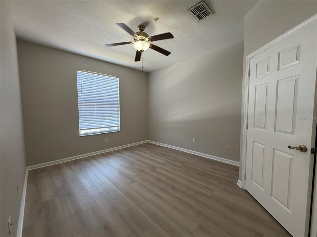 13524 Turtle Marsh Loop, Unit 621 Orlando, FL 32837 - Photo 7 of 14 an empty room with wooden floor chandelier fan and windows