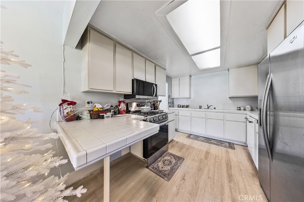 20200 Lassen Street Chatsworth, CA 91311 - Photo 25 of 32 a kitchen with kitchen island a sink appliances cabinets and a counter top space