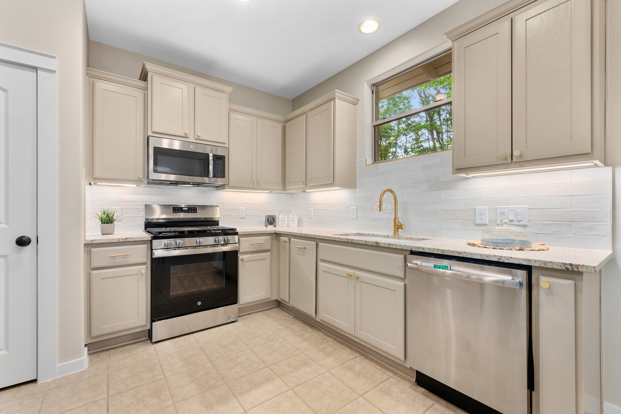 a kitchen with cabinets appliances a sink and a window