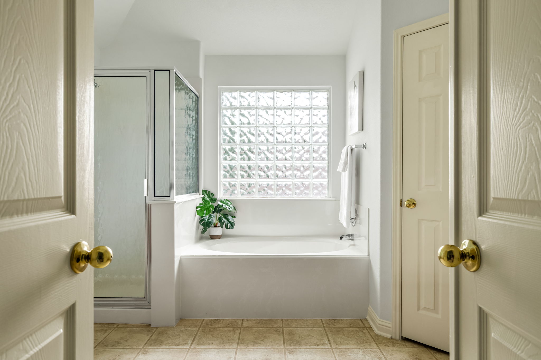 10004 Isle Royale Way Austin, TX 78747 - Photo 22 of 31 Relax in this well-lit primary bathroom featuring a spacious tub and glass block window for natural light.