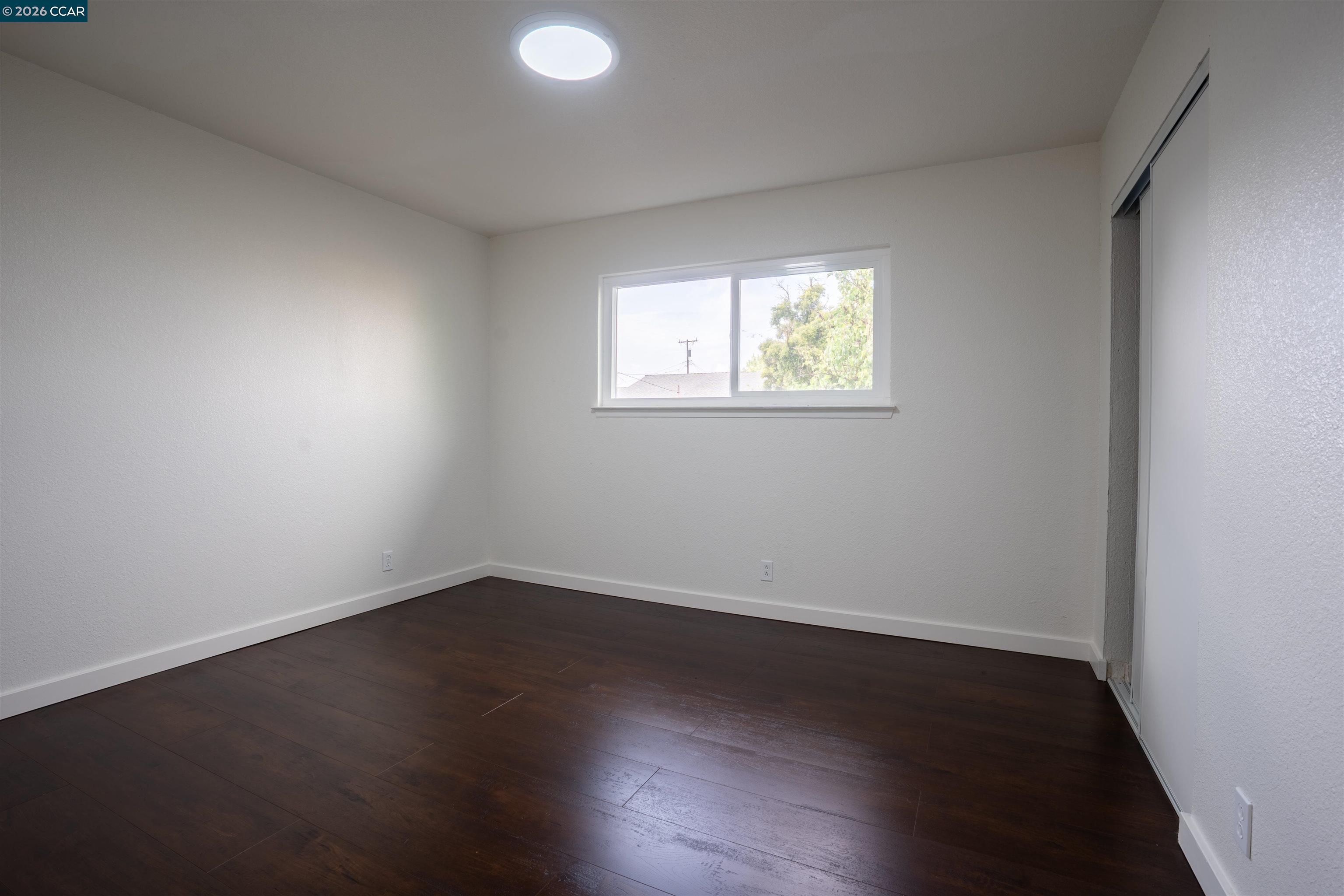58 Solano Avenue Bay Point, CA 94565 - Photo 8 of 23 an empty room with wooden floor and windows