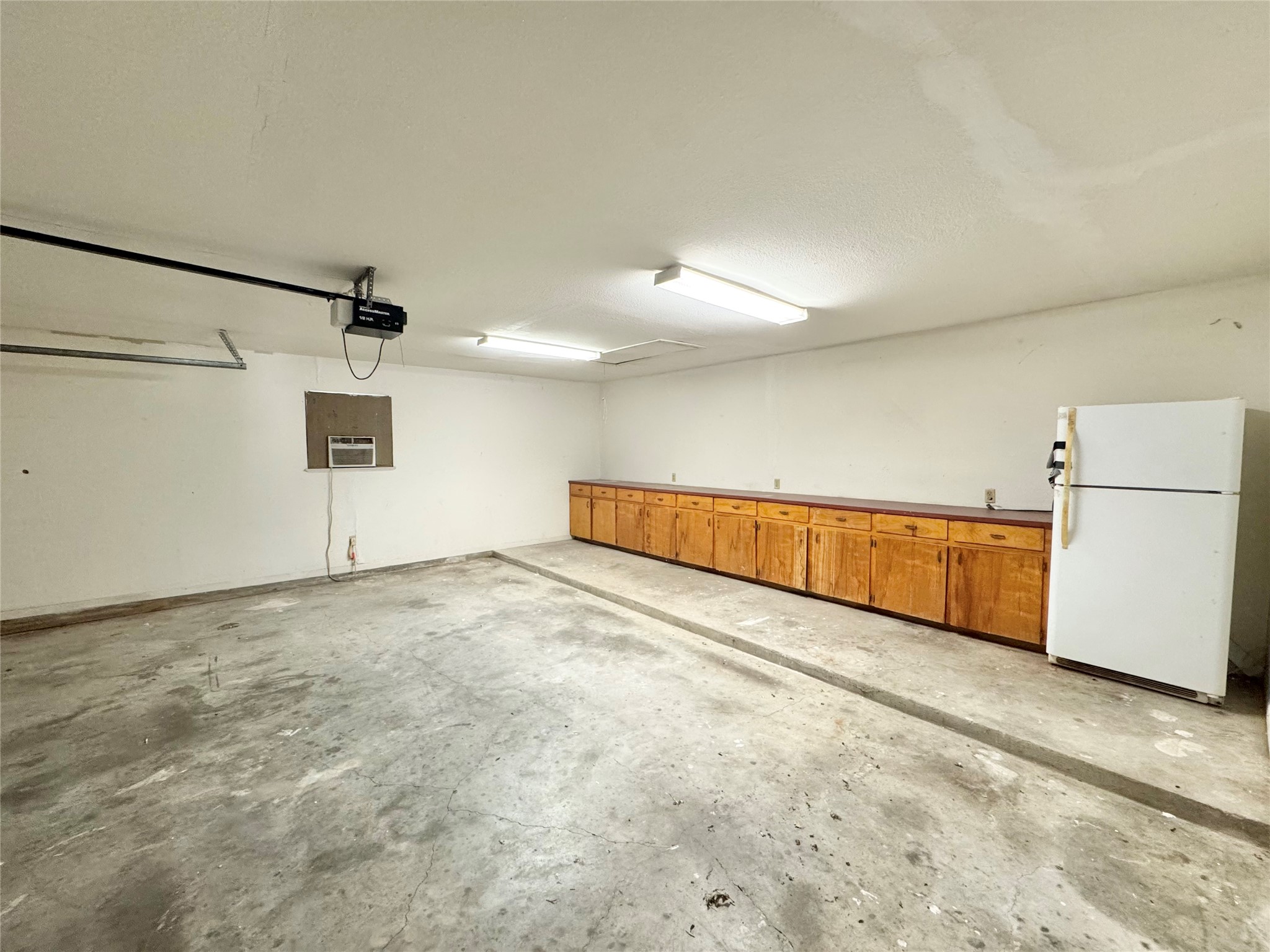 18512 Carlson Lane Elgin, TX 78621 - Photo 24 of 29 A spacious garage features concrete flooring, built-in wooden cabinetry, and an overhead door mechanism.