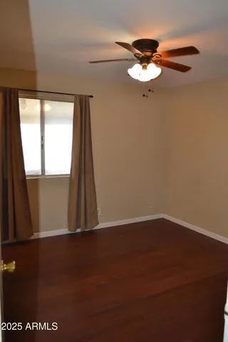 an empty room with wooden floor fan and window