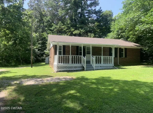 a view of a house with a backyard and a large tree