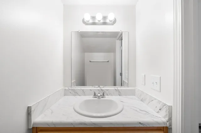a bathroom with a granite countertop sink and a mirror