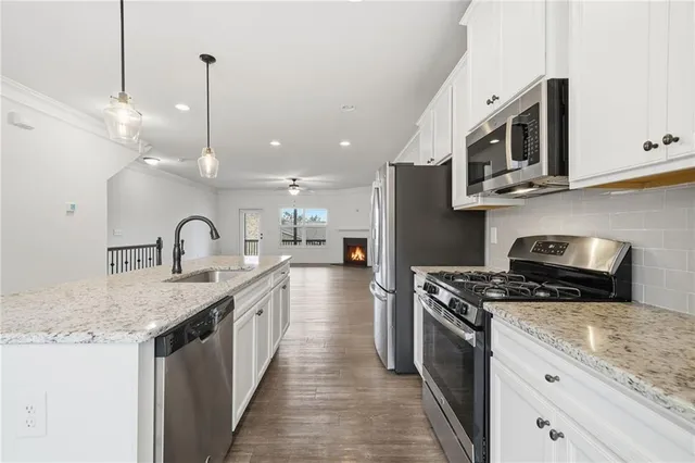 a kitchen with granite countertop a stove a sink and a microwave