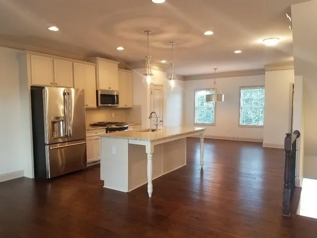 a kitchen with a refrigerator a stove top oven a sink a counter space and wooden floor