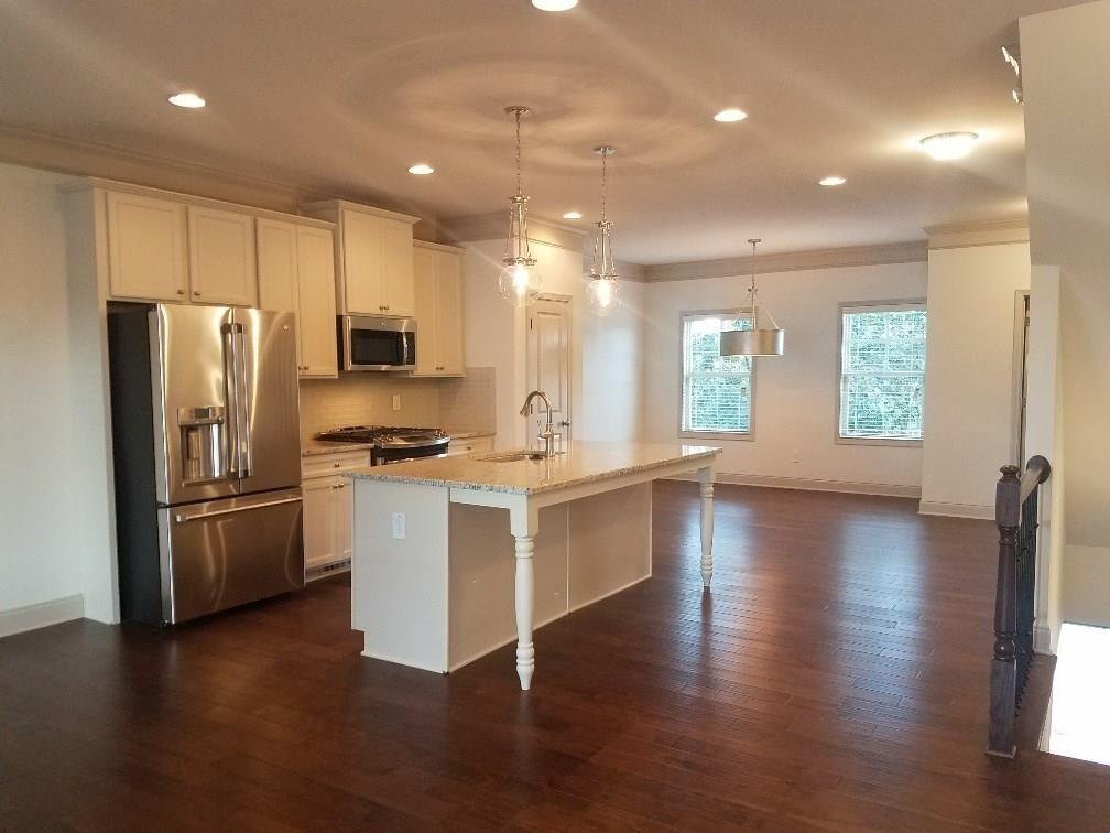 1450 Baygreen Road Suwanee, GA 30024 - Photo 4 of 7 a kitchen with a refrigerator a stove top oven a sink a counter space and wooden floor