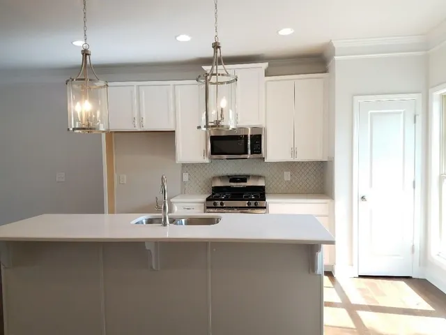 a kitchen with kitchen island granite countertop a sink a counter space appliances and cabinets